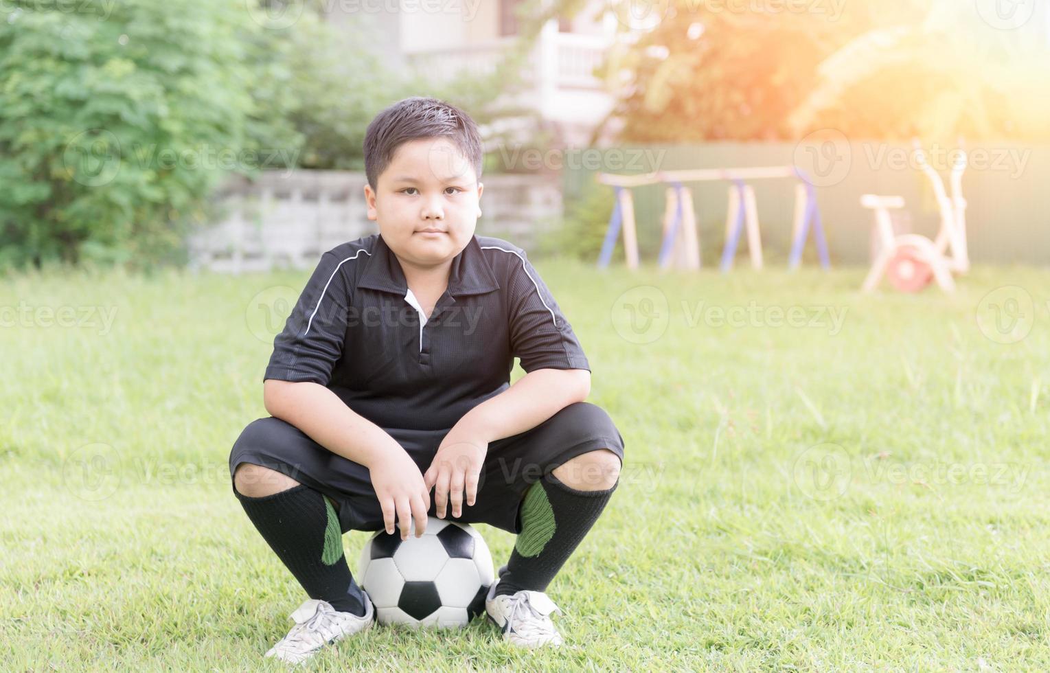 obeso gordo Garoto futebol jogador sentar em futebol foto