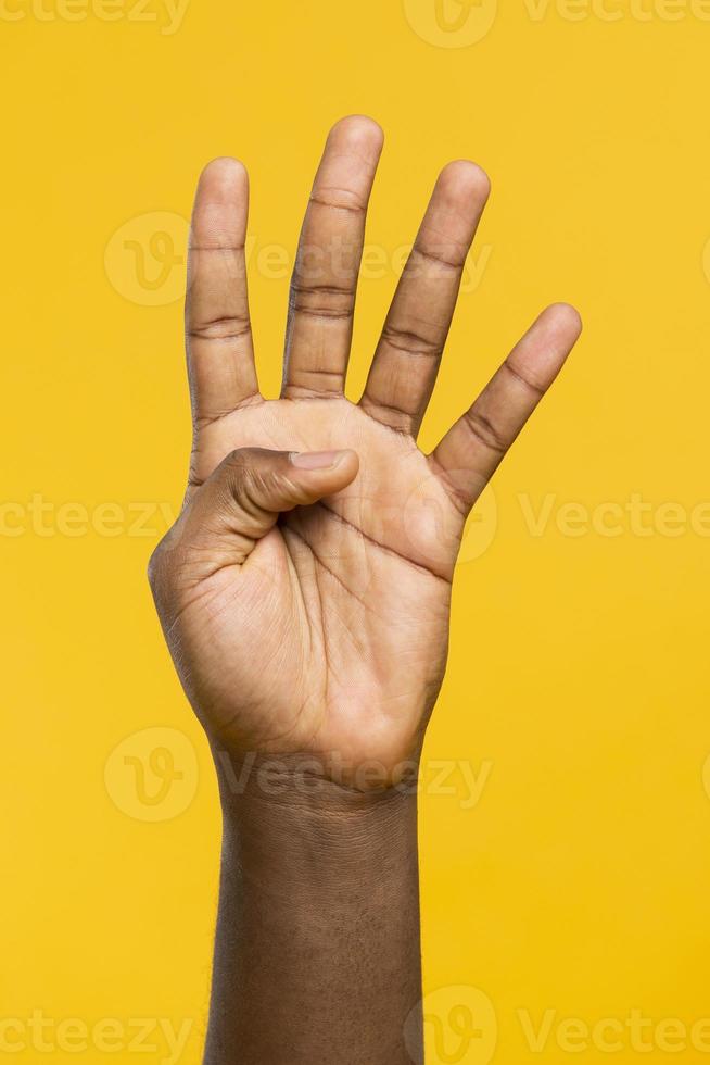 mão mostrando quatro dedos em fundo amarelo foto