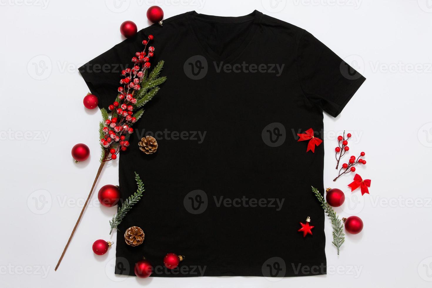 feche a camiseta modelo em branco preto com espaço de cópia e o conceito de férias de natal. t-shirt de maquete de vista superior e decorações vermelhas de feriados em fundo branco. feliz ano novo acessórios. roupa de natal foto