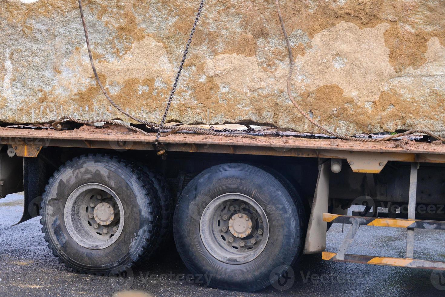 grande caminhão em estrada com enorme pedra foto