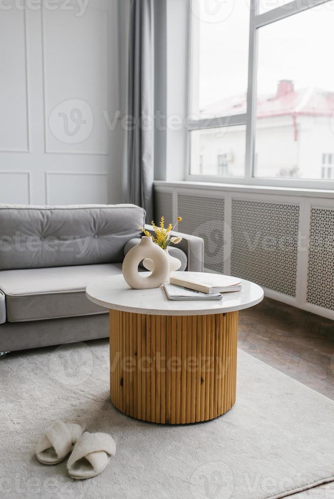 de madeira café mesa com mármore topo dentro a interior do uma moderno vivo quarto com uma cinzento sofá foto