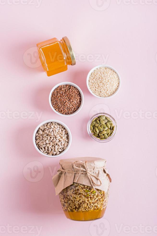 saudável mistura do querida e vários sementes dentro uma jarra e ingredientes para cozinhando topo e vertical Visão foto