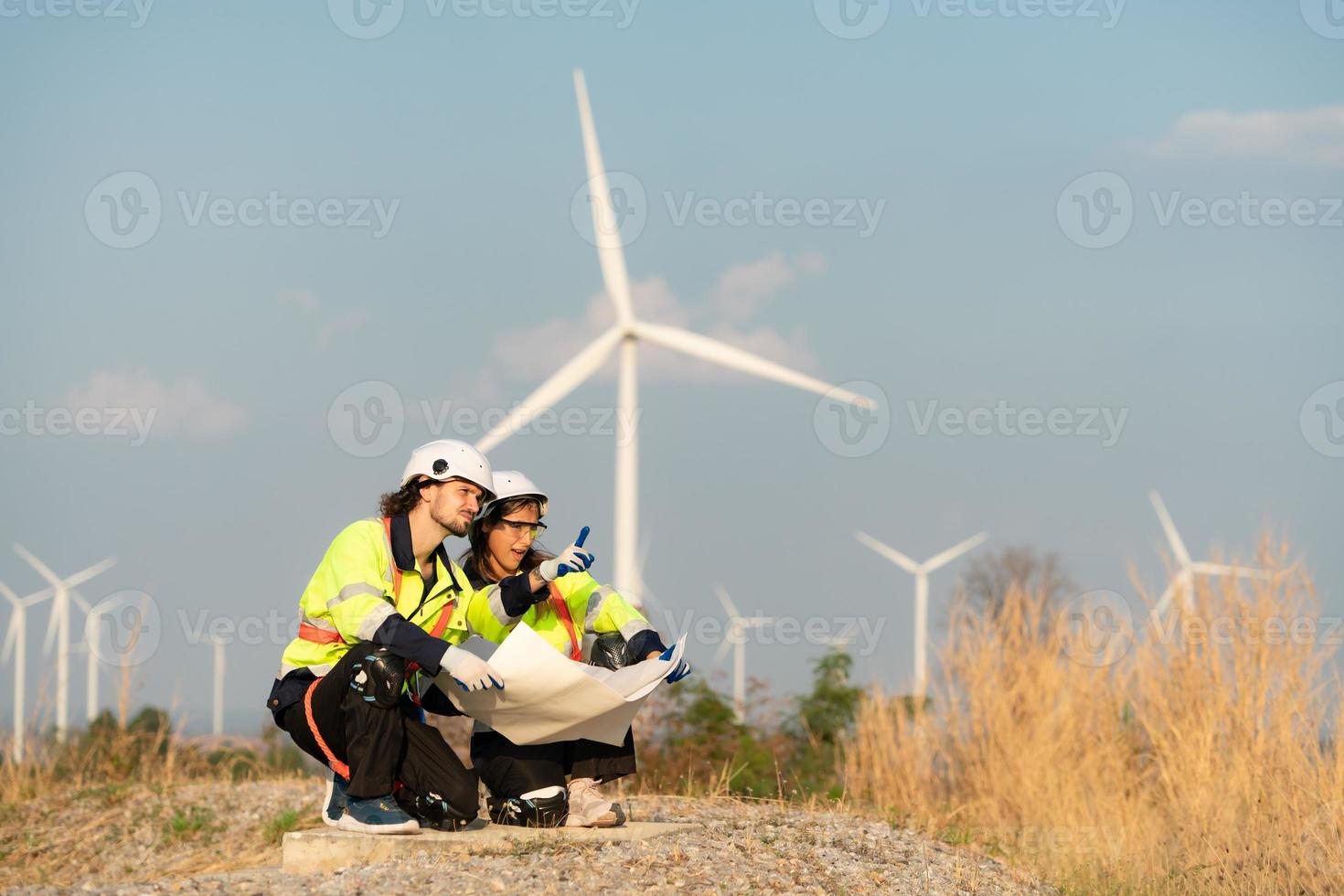 homem e fêmea engenheiro estacionado às a natural energia vento turbina local. com diariamente auditar tarefas do principal vento turbina operações este transformar vento energia para dentro elétrico eletricidade foto