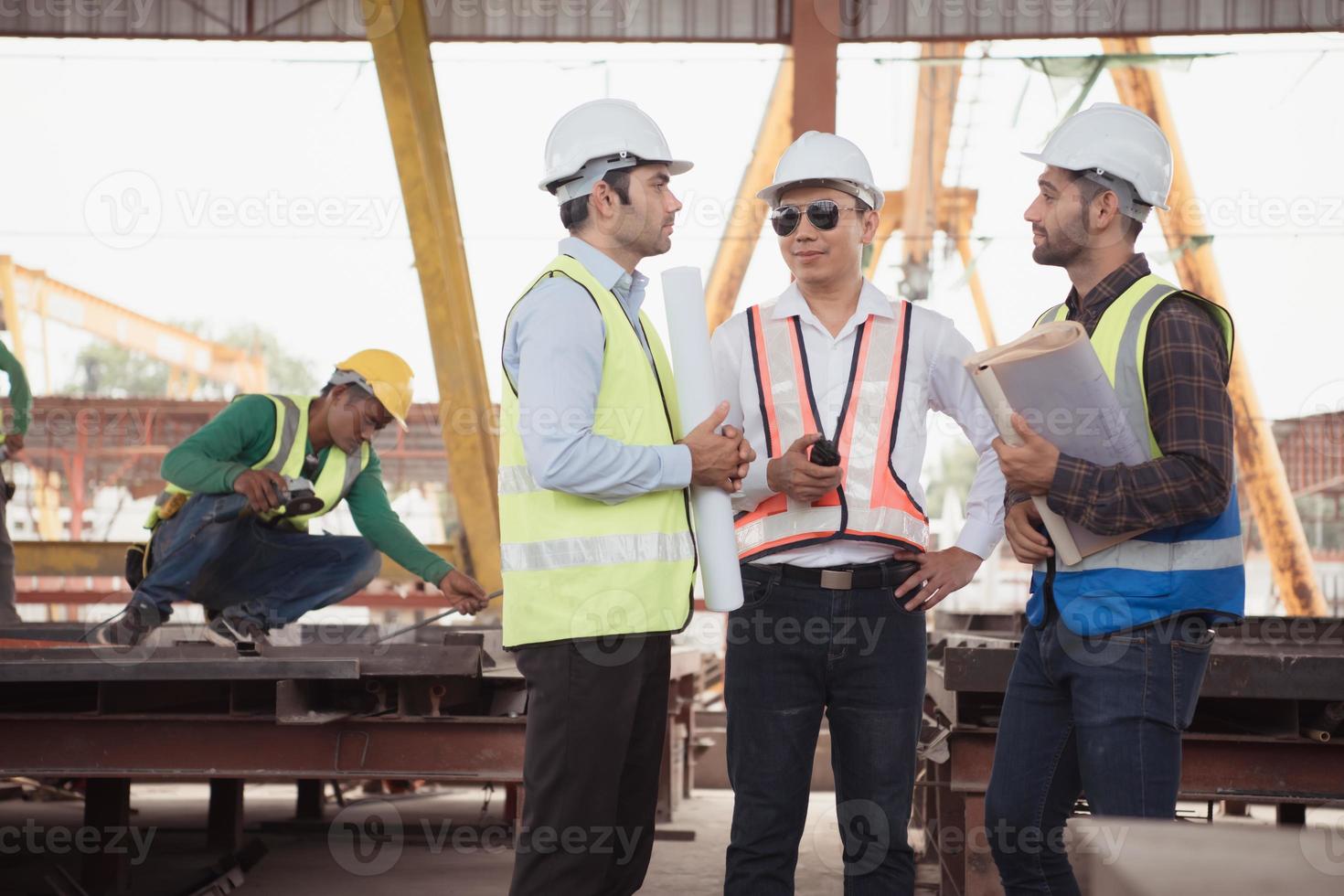 grupo do arquitetos, construção capatazes, e construção engenheiros Reveja a trabalhos e conversa sobre quão a projeto, dentro a construção local. foto