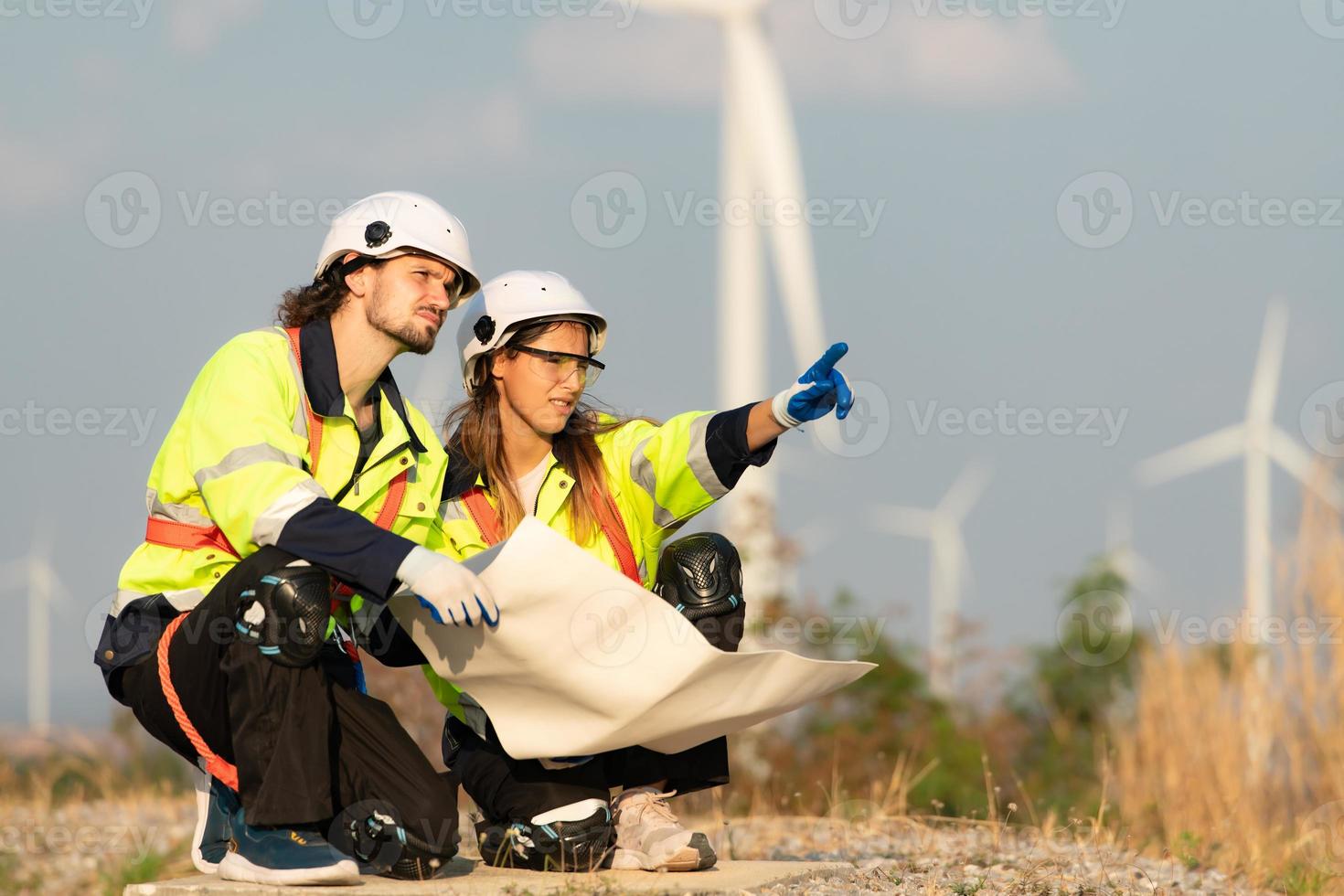 homem e fêmea engenheiro estacionado às a natural energia vento turbina local. com diariamente auditar tarefas do principal vento turbina operações este transformar vento energia para dentro elétrico eletricidade foto