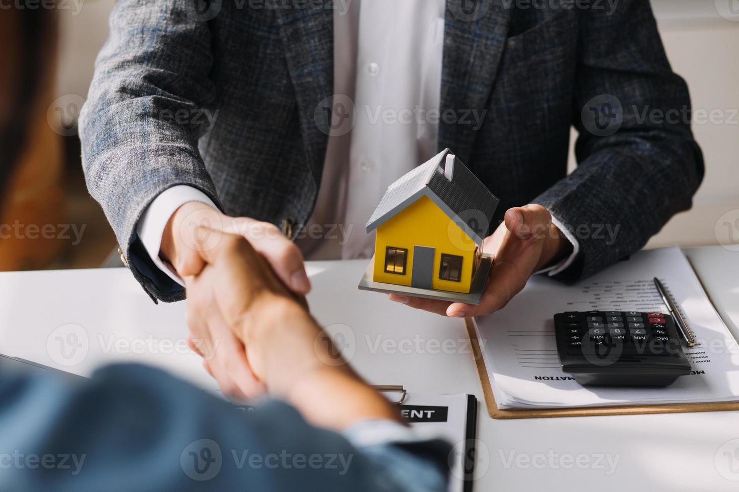 mãos de mulher feminina segurando modelo de casa, pequena casa de brinquedo branco em miniatura. sonho de seguro de propriedade hipotecária movendo-se para casa e conceito imobiliário foto