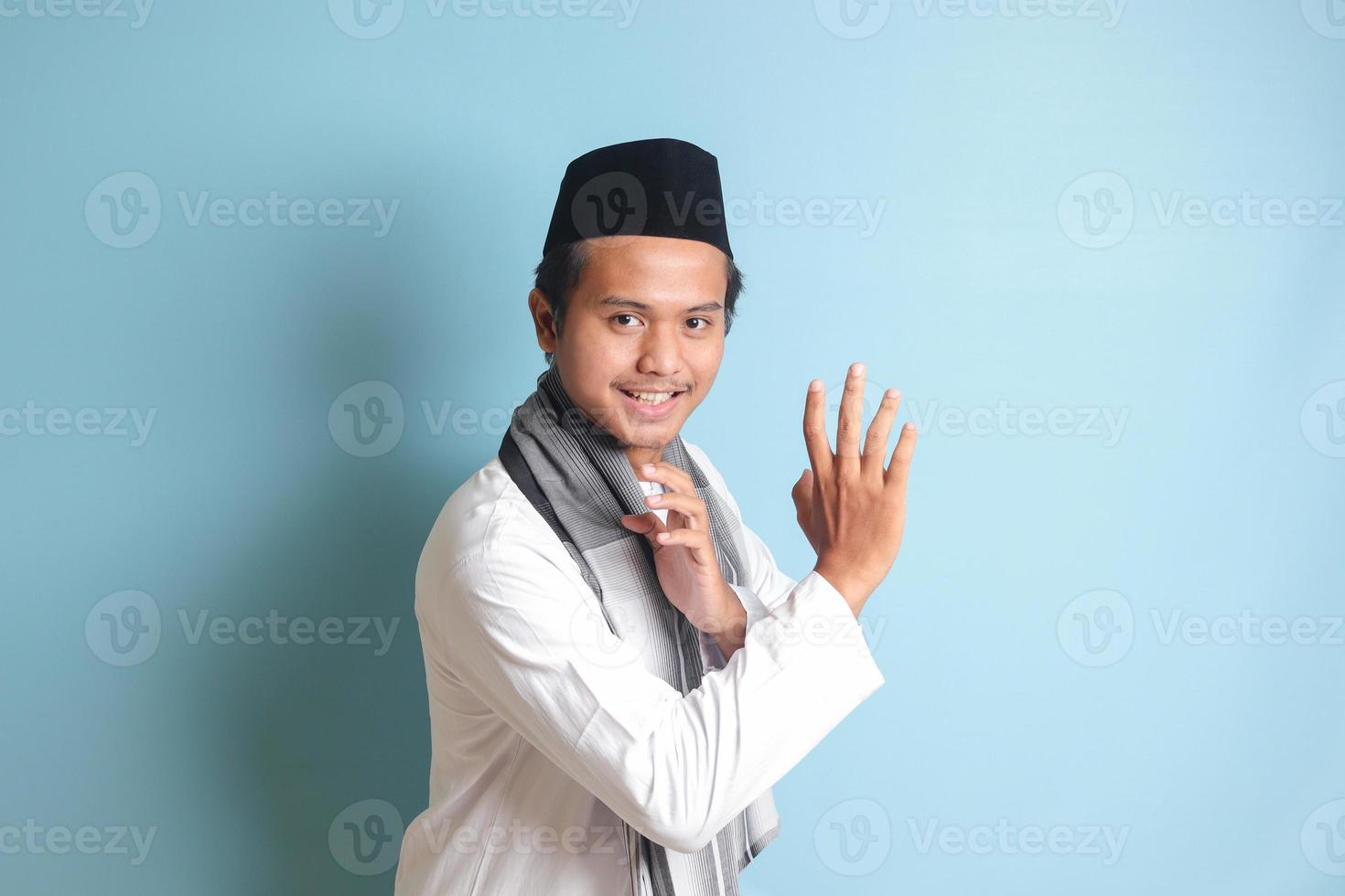 retrato do ásia muçulmano homem dentro branco Koko camisa fazendo marcial artes gesto ou pencak silat. isolado imagem em azul fundo foto