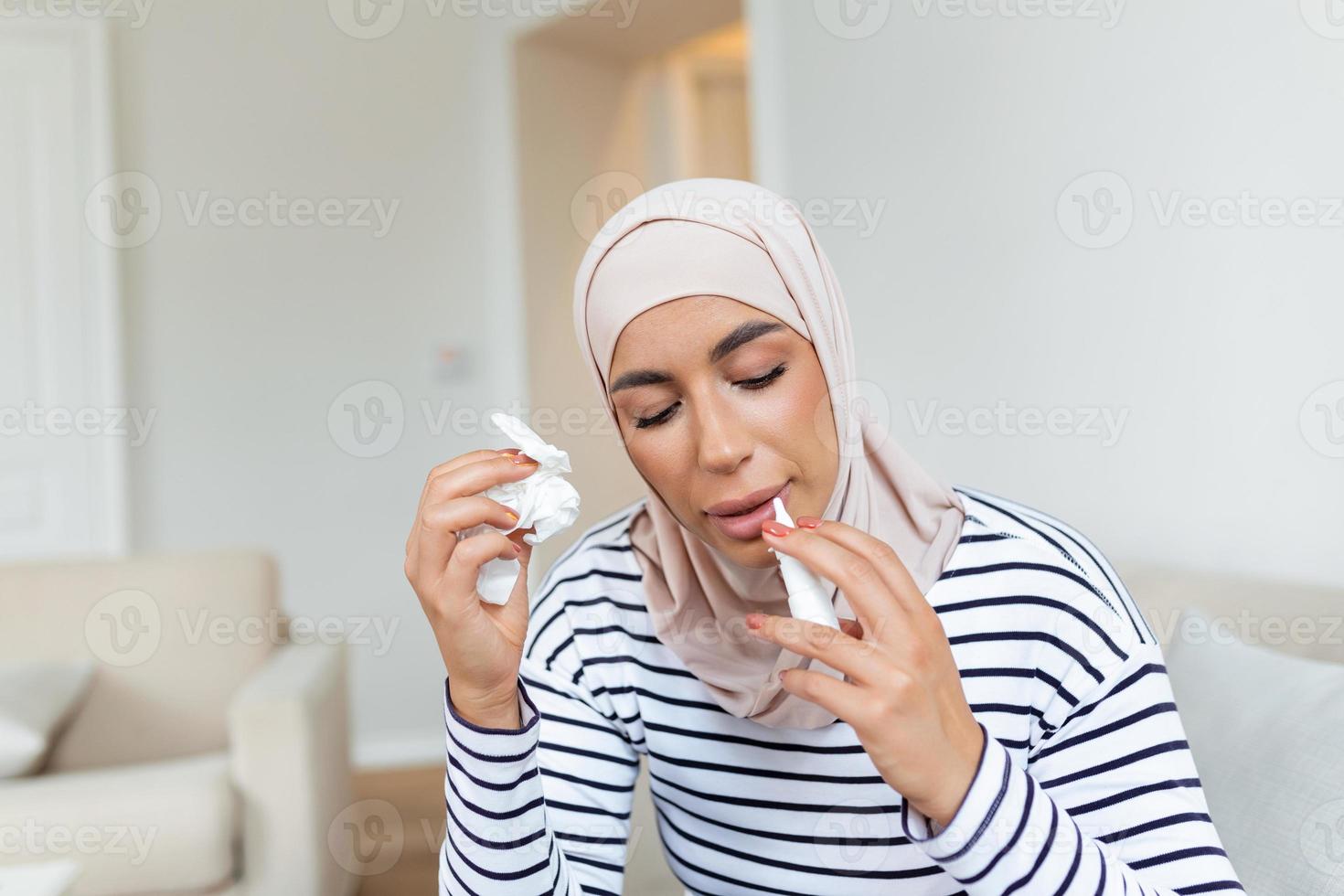 doente árabe mulher com hijab é usando nasal spray vencimento para a problemas com nariz e respiração foto