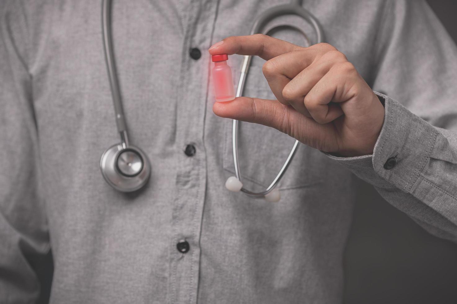 o médico segura um frasco de vacina para matar a doença foto