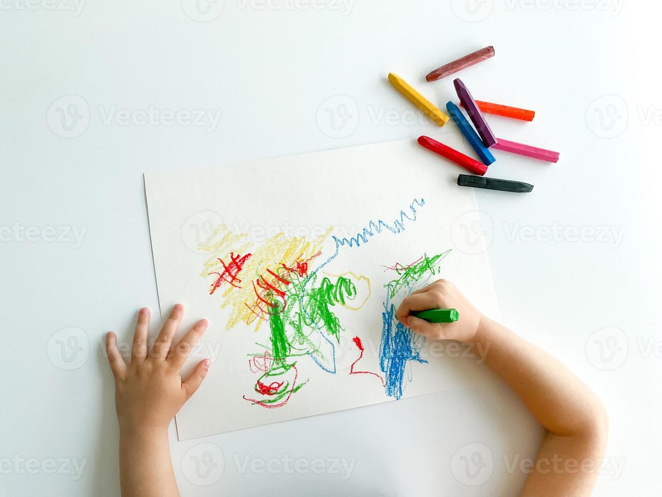 pequeno criança desenha com pastel giz de cera em branco mesa. pais dia foto