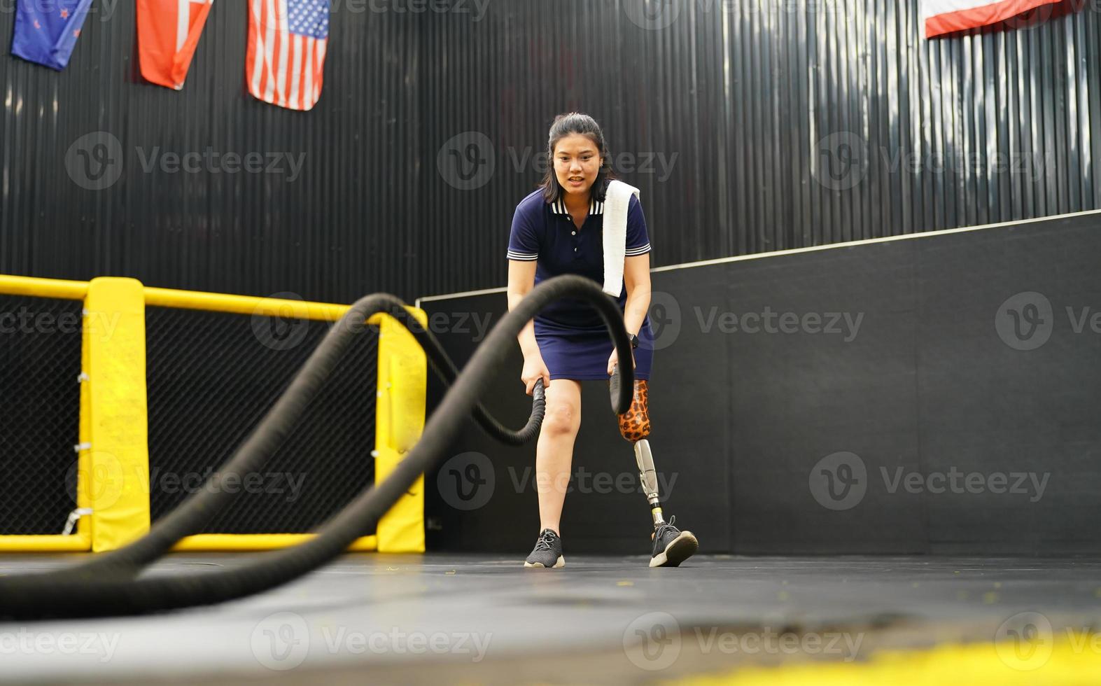 jovem fêmea com 1 protético perna com fazendo braço e ombro exercícios com uma corda para prática balanceamento com protético perna, conceito do vida do mulheres com protético pernas. foto