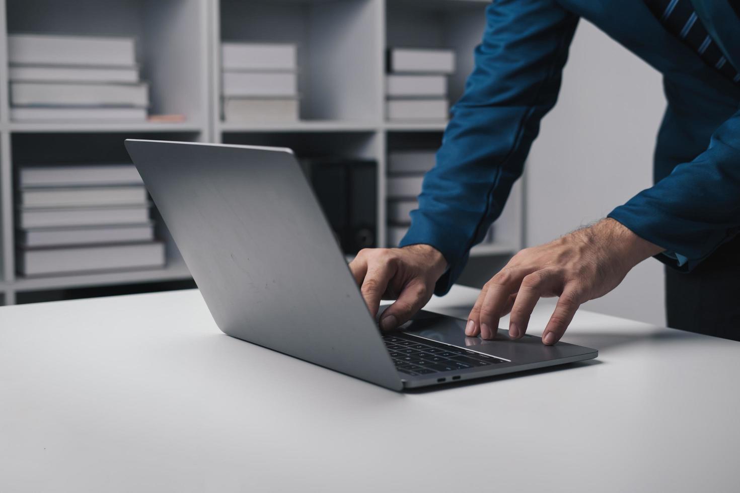 fechar acima Visão do homem de negocios usando computador portátil computador às escritório escrivaninha dentro a escritório sala. foto