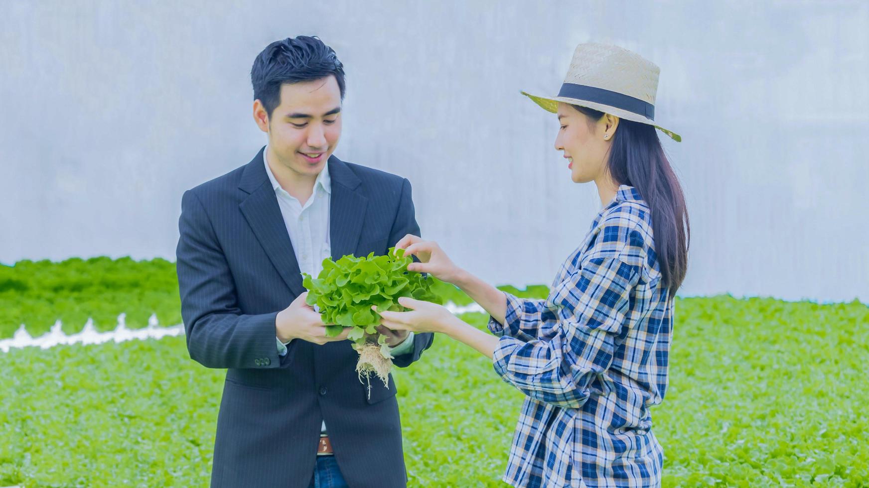 jovem gerente e um lindo jovem agricultor estão trabalhando para verificar a qualidade dos vegetais foto