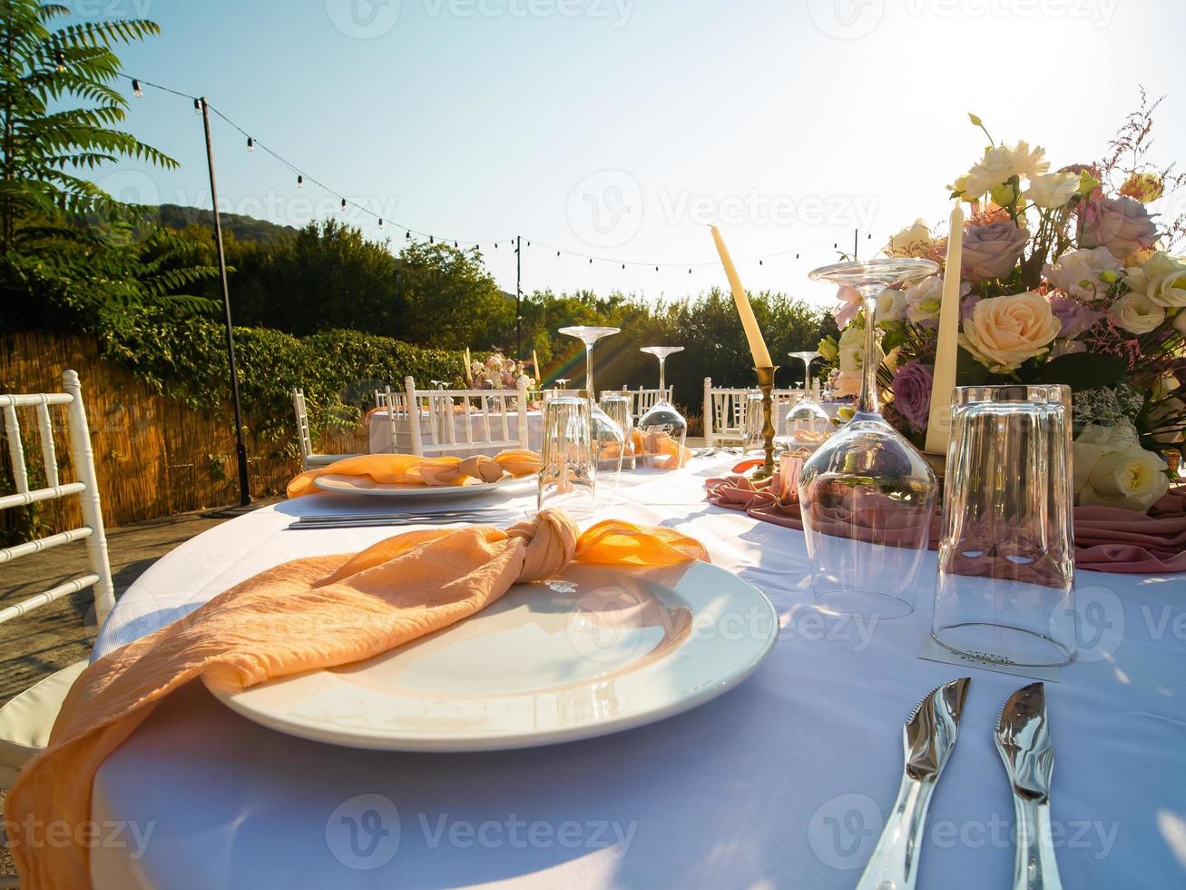 lindo ao ar livre Casamento decoração dentro cidade. velas e seco flores e acessórios com buquês e óculos em mesa com linho toalha de mesa em recém-casado mesa em verde gramado foto