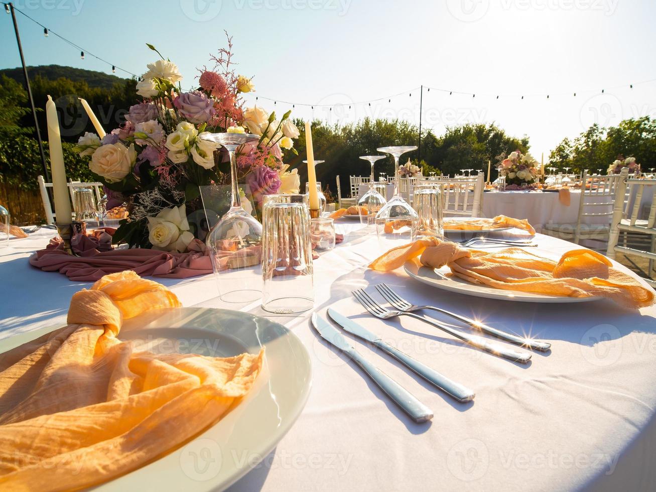 mesa às luxo Casamento recepção evento. lindo flores em mesa e servindo pratos e óculos e decoração foto