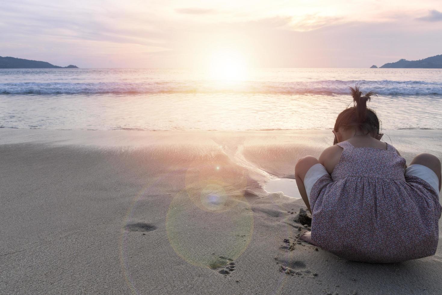 menina brincando na areia ao pôr do sol foto