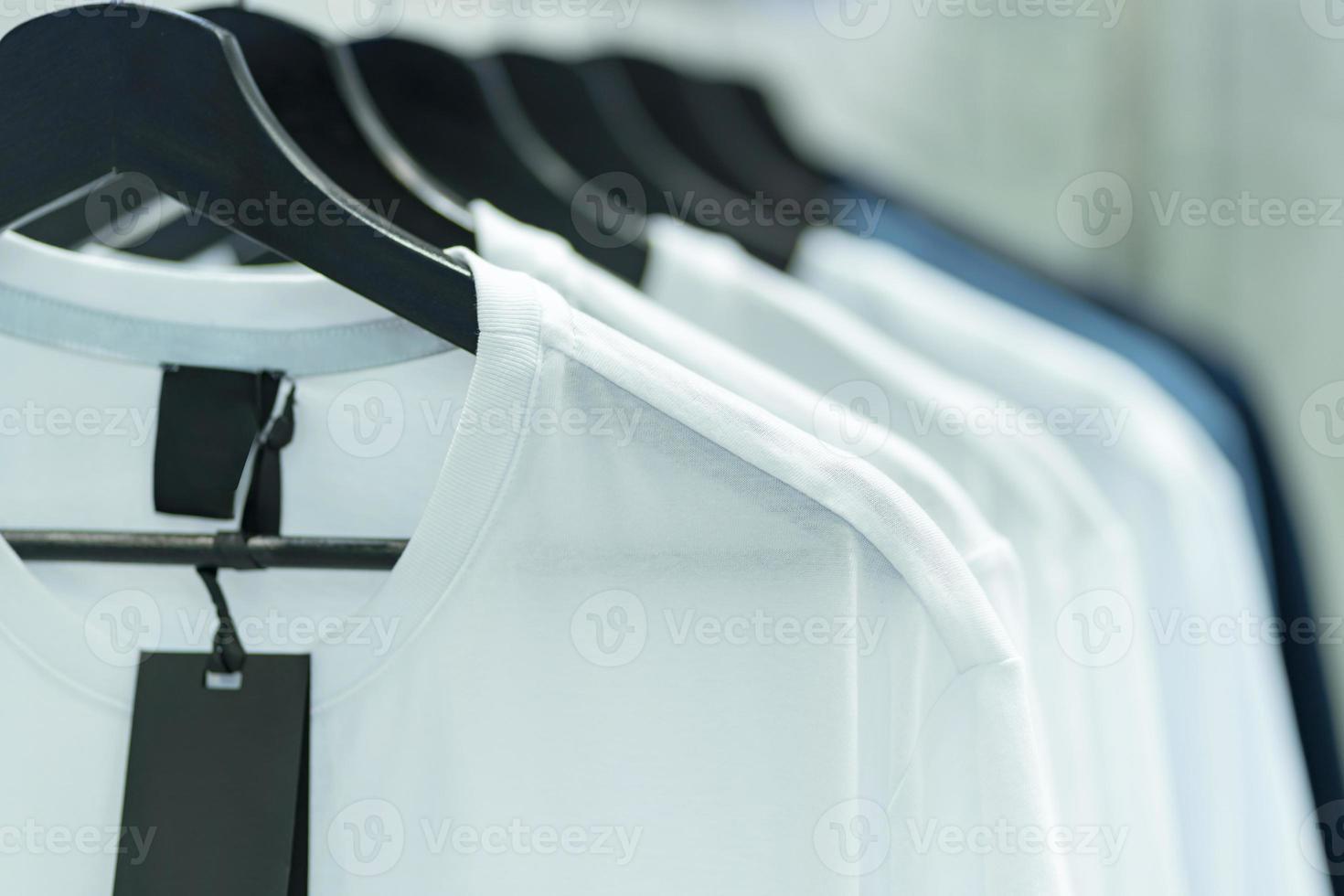 close-up de camisetas brancas em cabides, fundo de vestuário foto