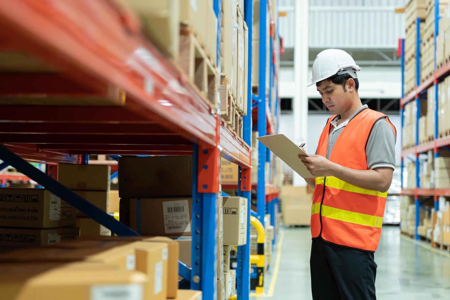 ásia masculino fábrica Gerente inspecionar bens dentro armazém ou inventário e Verifica estoque produtos. transporte logístico o negócio envio, Entrega para clientes. inspeção, armazém, armazenar, fábrica foto