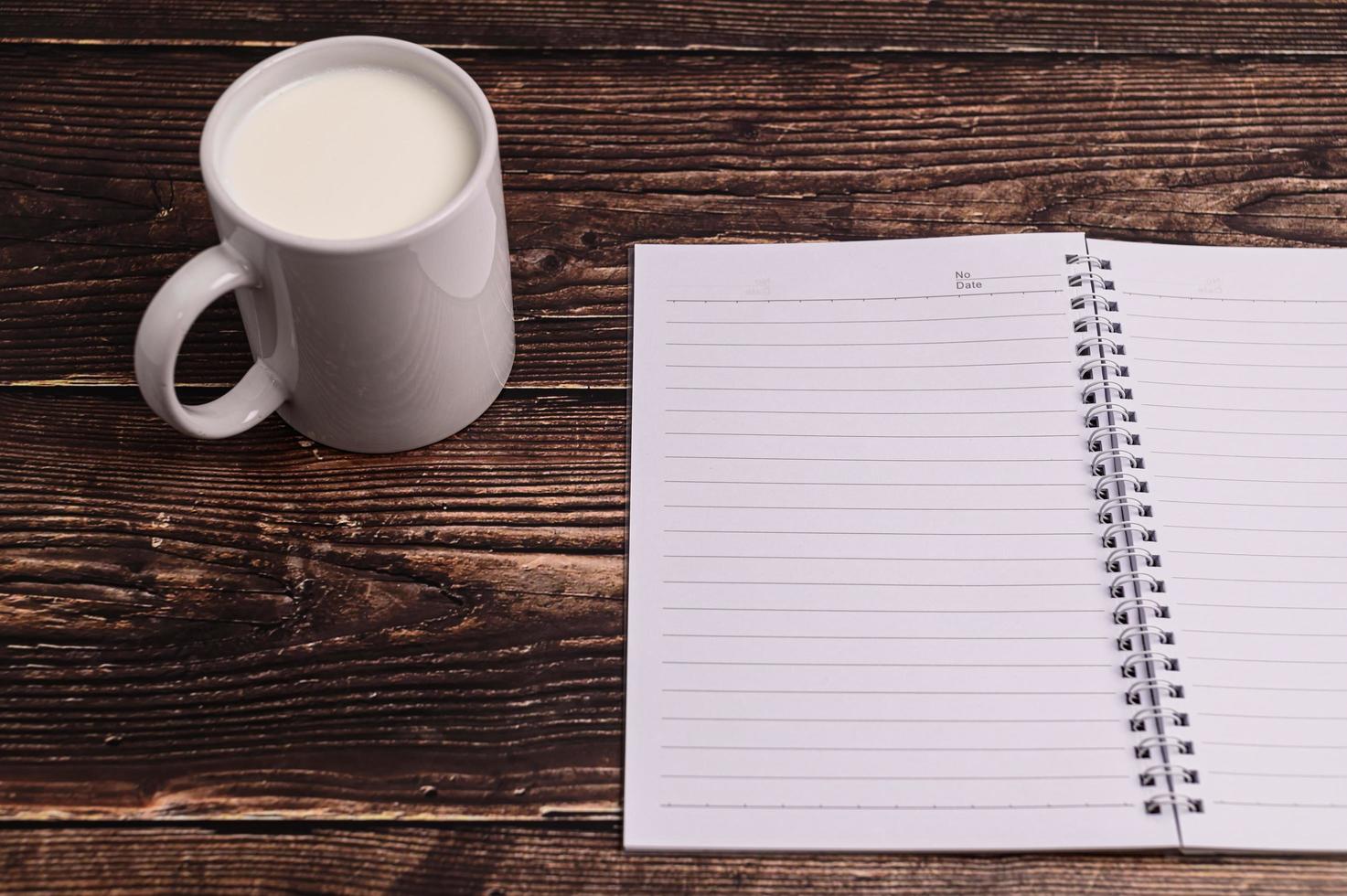 caderno e um copo de leite na mesa foto