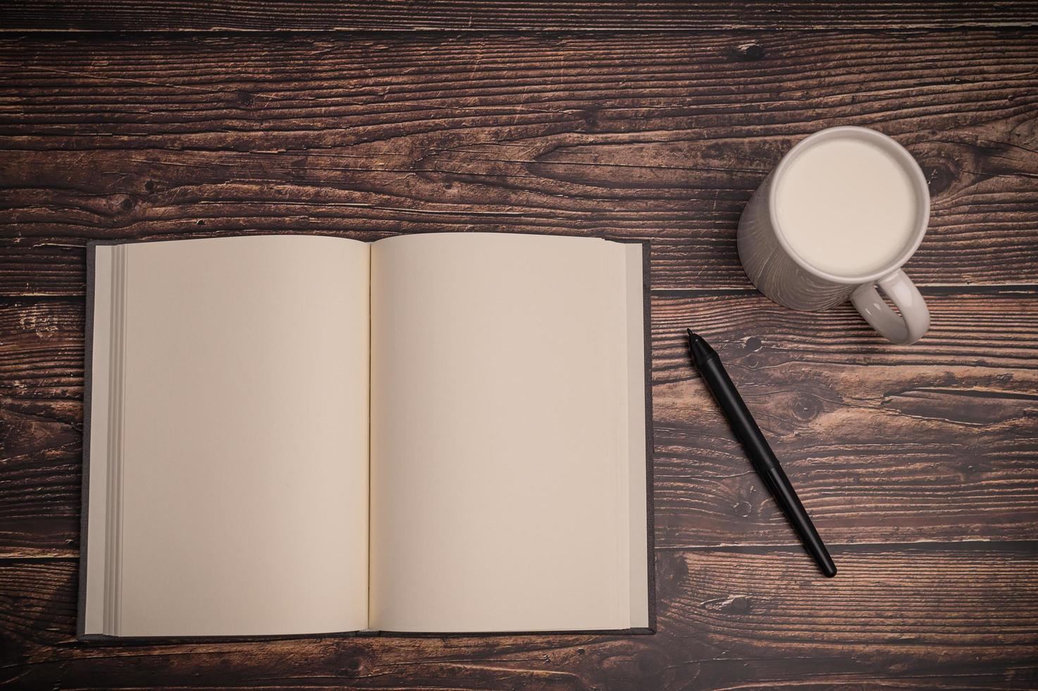 caderno e um copo de leite na mesa foto