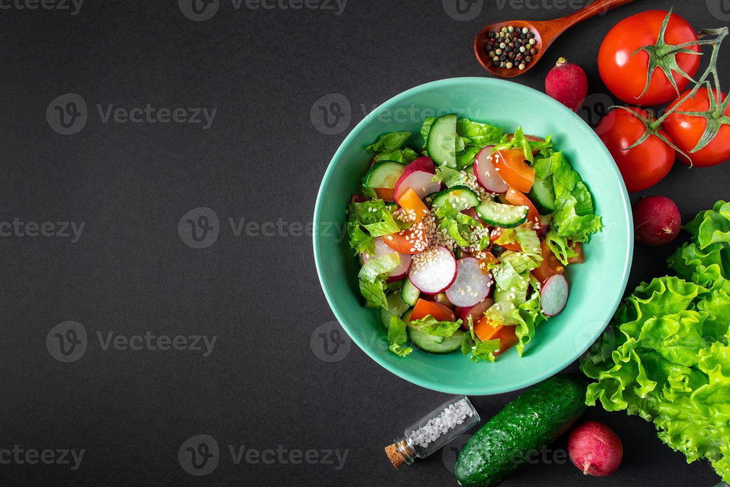 salada de legumes fresca em uma tigela de cerâmica em fundo cinza foto