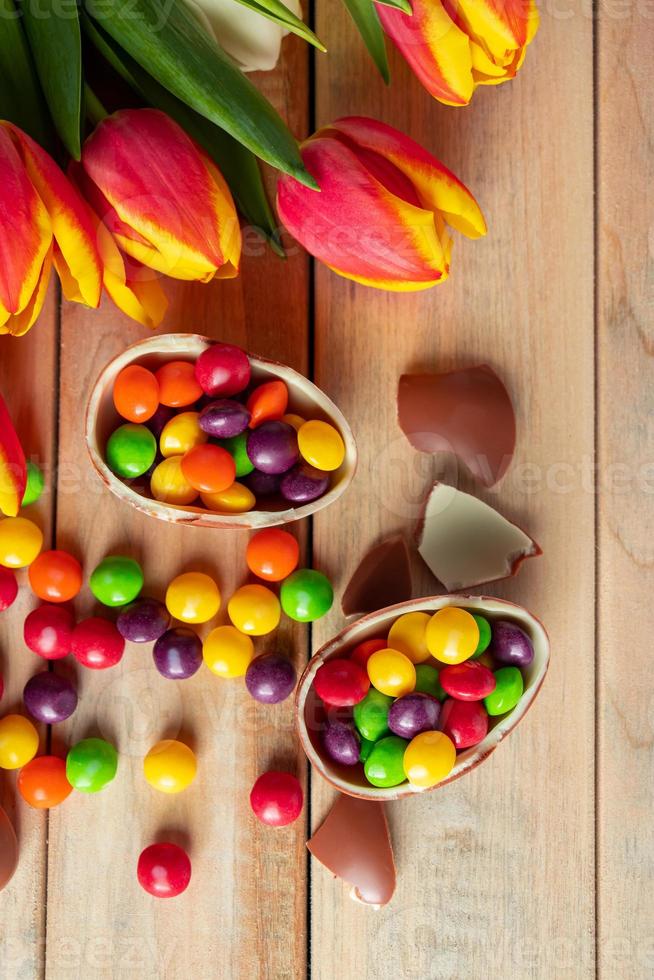 tulipas multicoloridas e ovos de páscoa de chocolate em um fundo de madeira foto