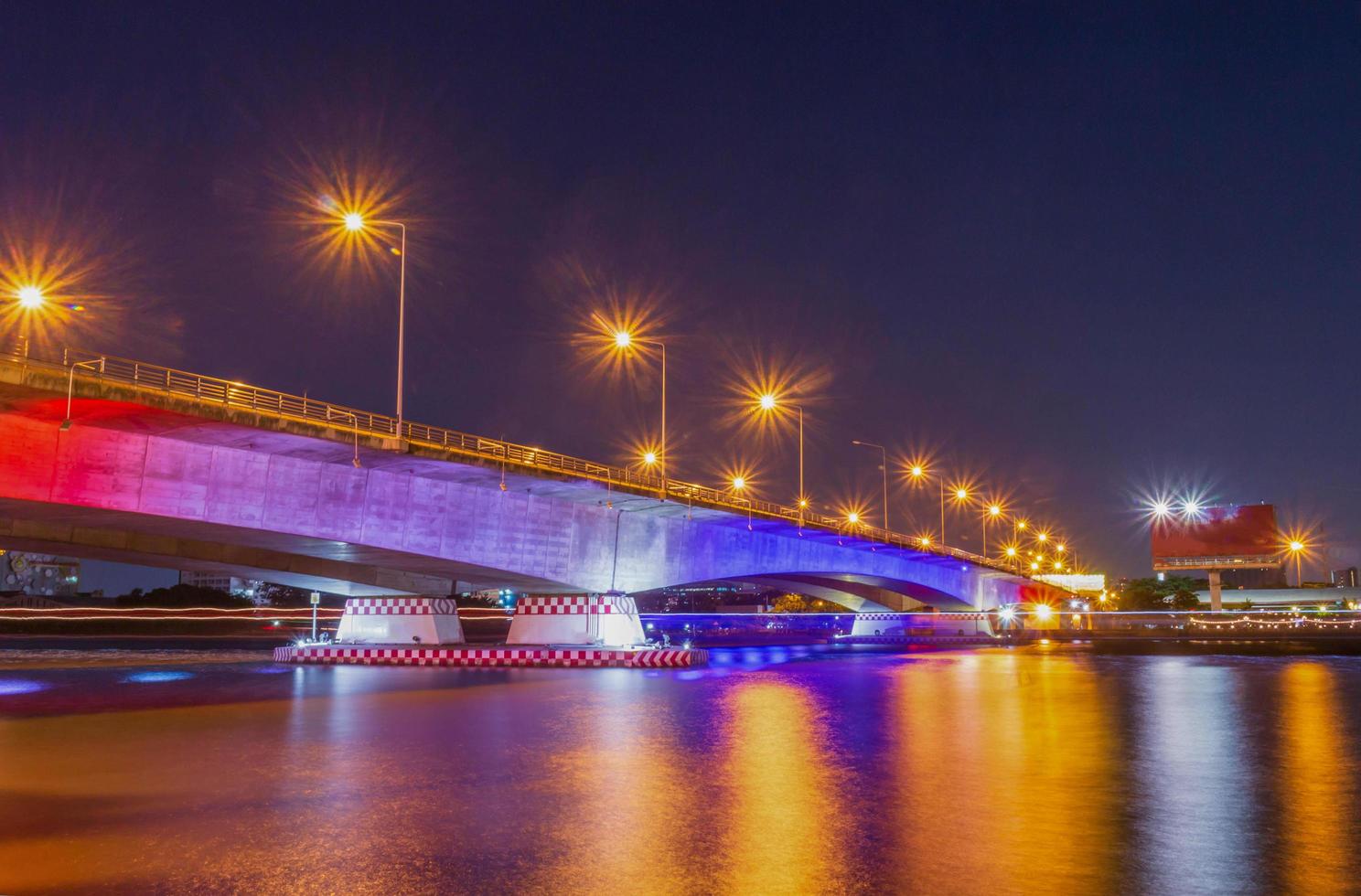 ponte lindamente iluminada sobre o rio à noite e um reflexo de água foto