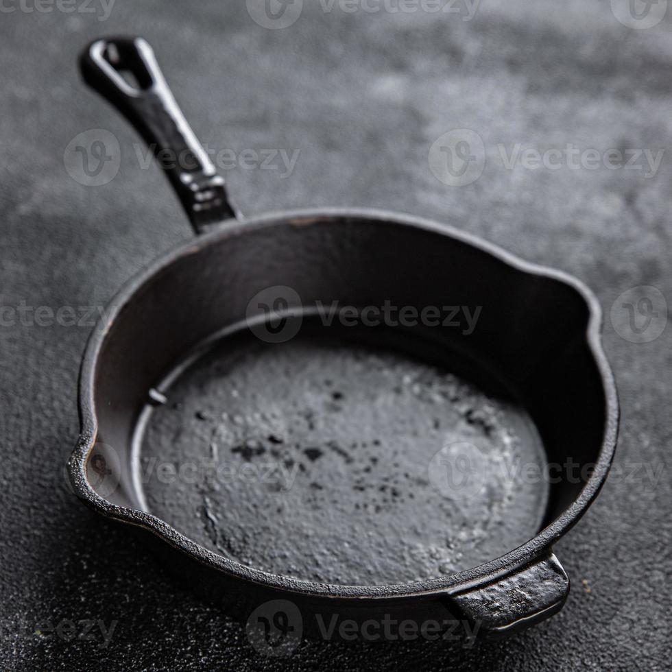 fundida ferro panela cozinha cozinhando equipamento fritar panela em a mesa Sombrio fundo cópia de espaço Comida fundo foto