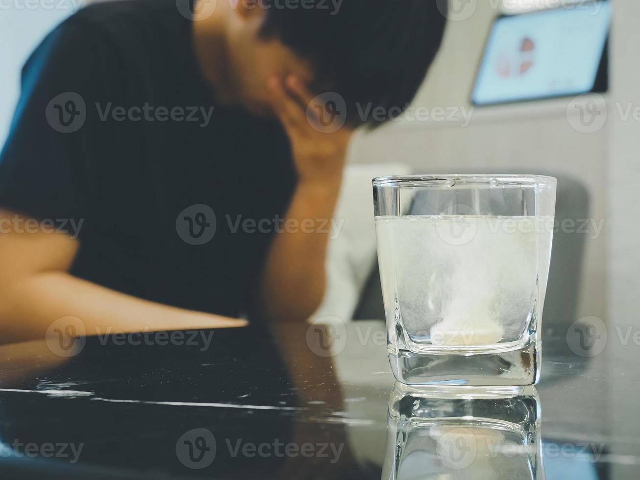 água solúvel efervescente comprimidos anti-flatulência pílulas, dor de cabeça alívio, multivitamínico. borrado fundo, homem tendo dor de cabeça a partir de trabalhar. foto