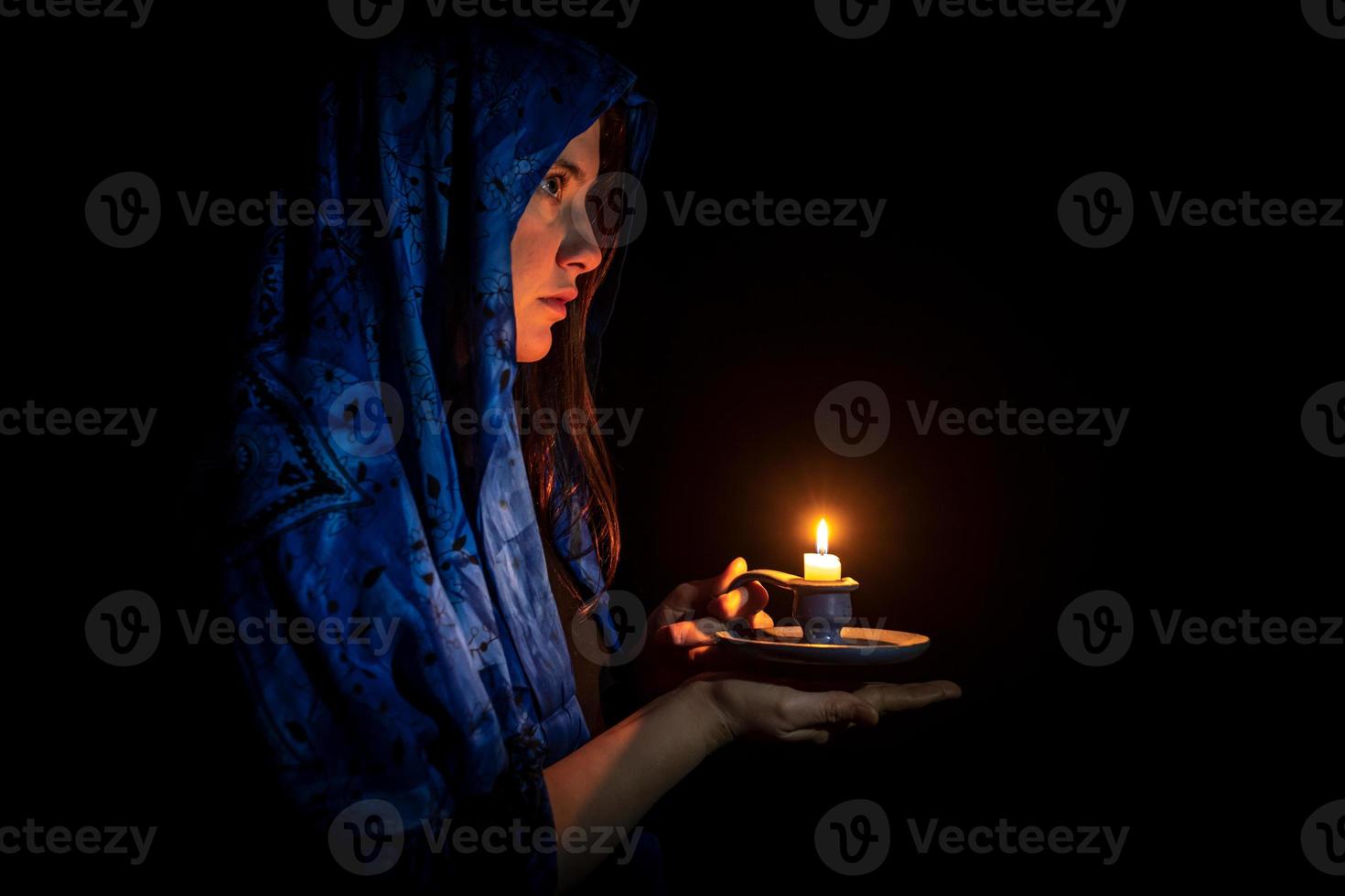 jovem triste com vela e lenço azul na cabeça foto