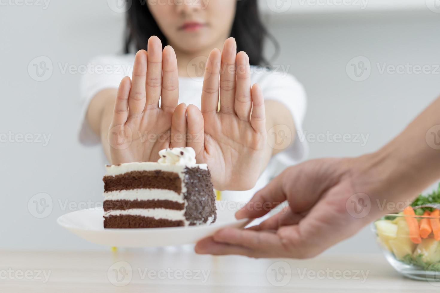 dieta, dieta pouco saudável ásia jovem mulher mão dentro empurrar fora, rejeitando comer chocolate bolo ou doce gosto, brigando para manter isto a partir de obtendo gordo quando pessoa trazer para meu. saudável, nutrição do peso perda foto