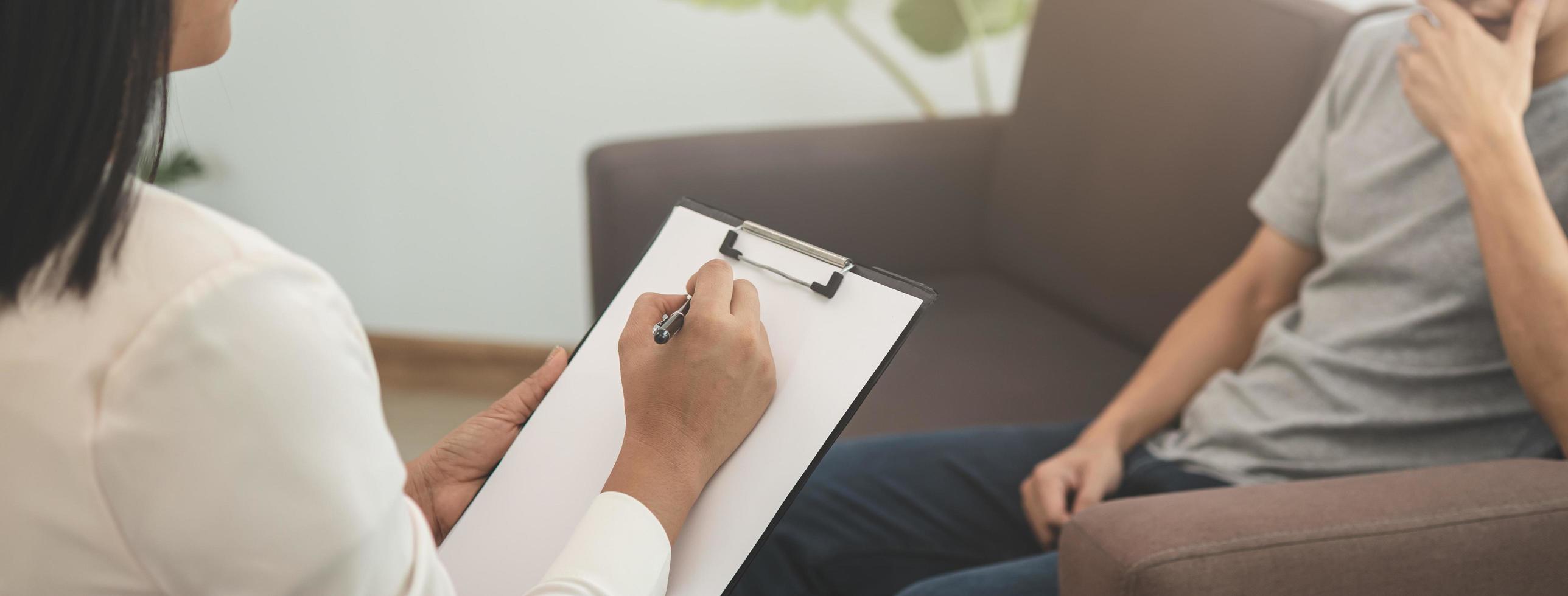 doente, doença ásia jovem mental homem sintoma que devo ter fui terapia, estresse, sentar em sofá consultar com psicólogo, médico mulher levar notas tratar de terapeuta às clínica. saúde Cuidado, triste pessoas. foto