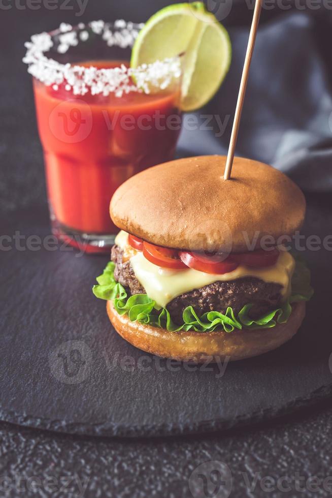 hambúrguer com um copo de suco de tomate foto