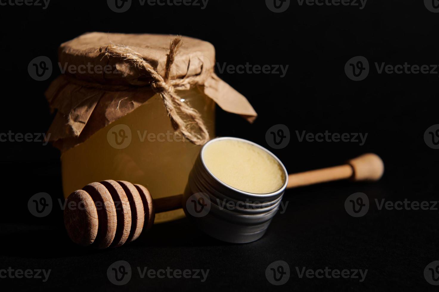 ainda vida com orgânico querida dentro vidro jarra, pode com cera e de madeira querida colher, isolado em Preto fundo foto