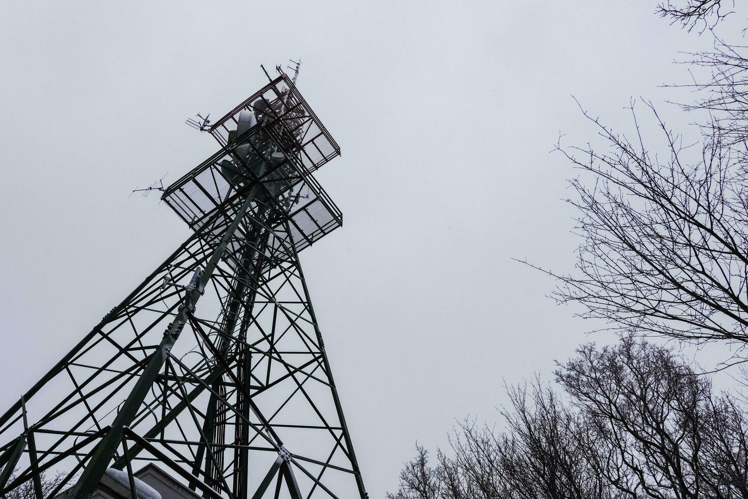 transmissão torre às uma montanha com cinzento céu foto