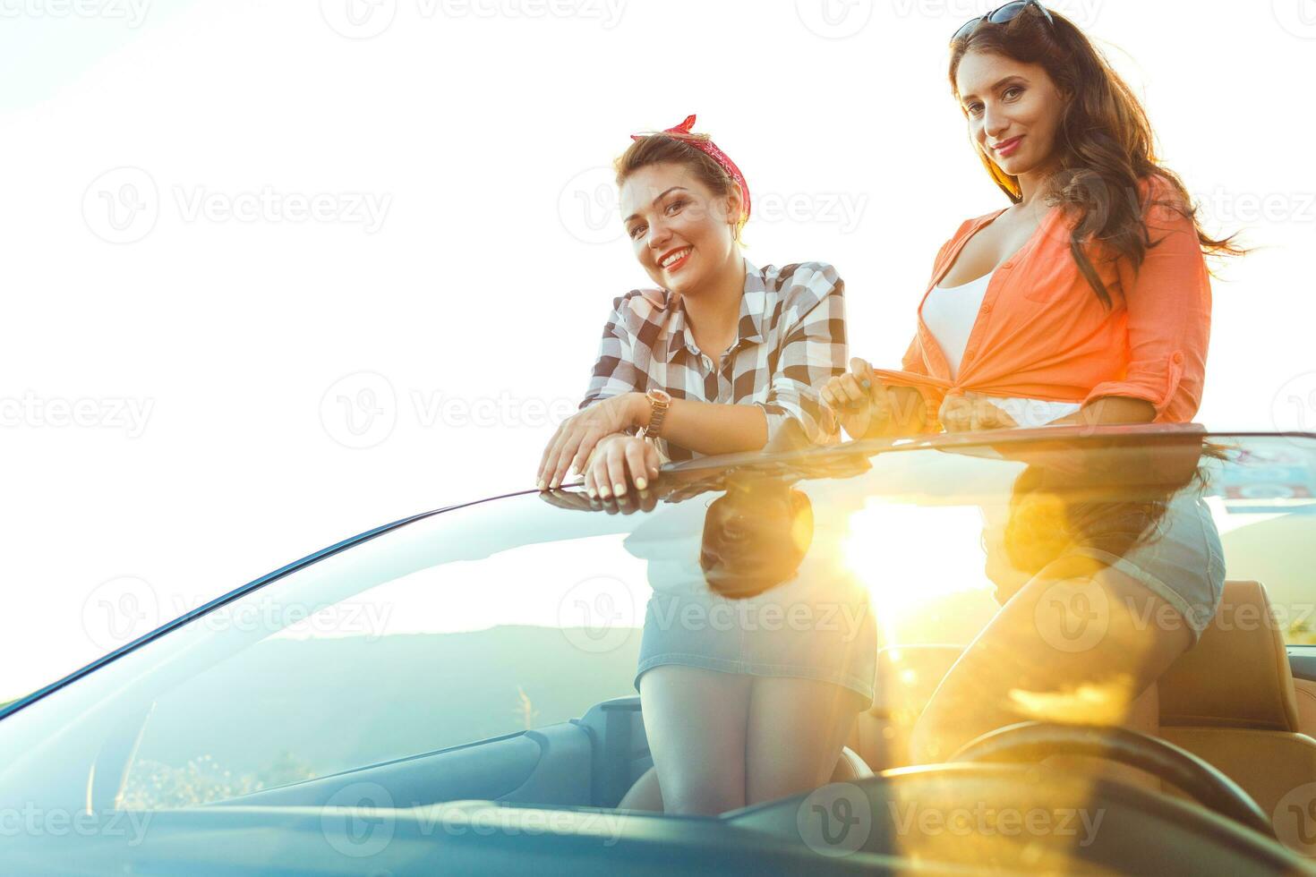 dois jovem feliz meninas tendo Diversão dentro a cabriolet ao ar livre foto
