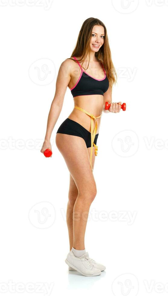 lindo Atlético mulher com halteres e medindo fita em cintura fazendo esporte exercício foto