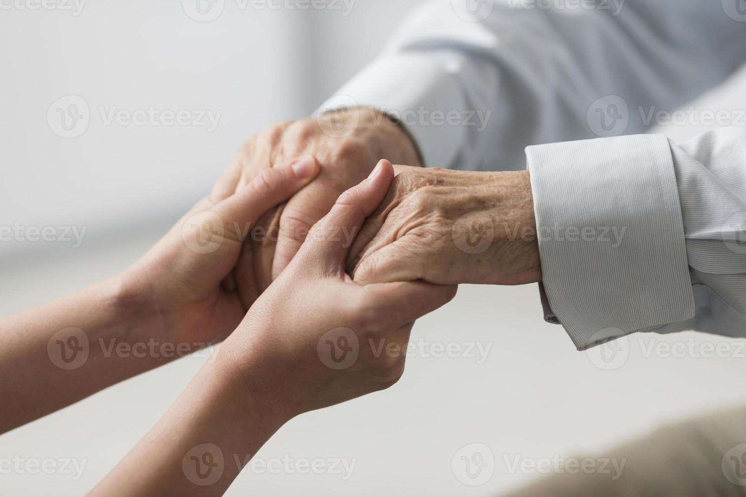 enfermeira segurando as mãos do homem sênior com simpatia foto