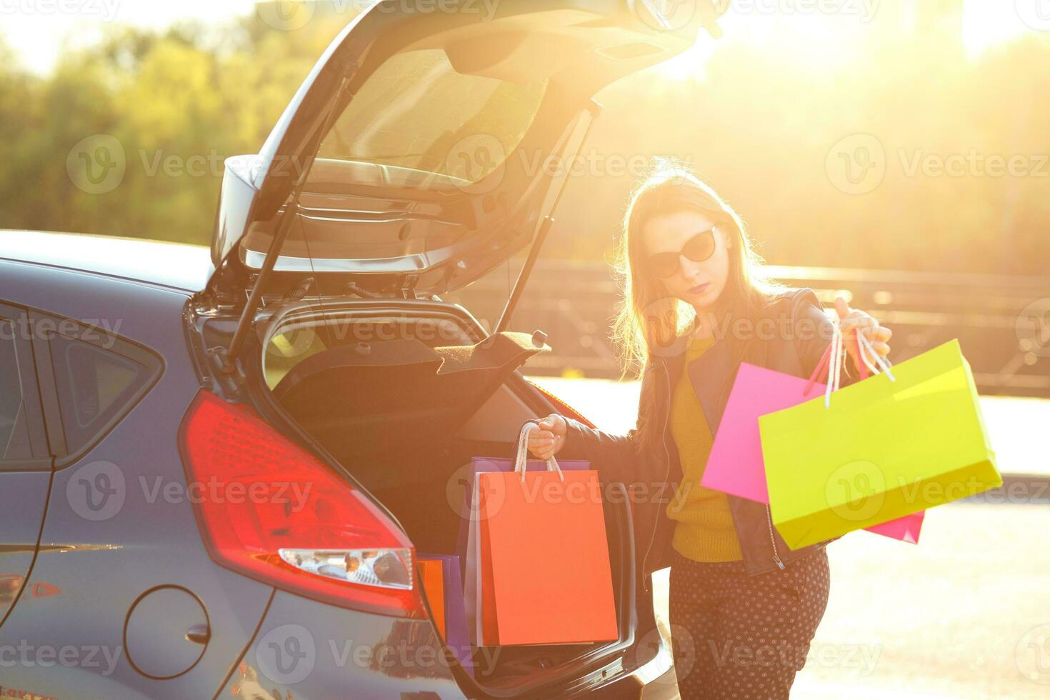 caucasiano mulher colocando dela compras bolsas para dentro a carro tronco foto