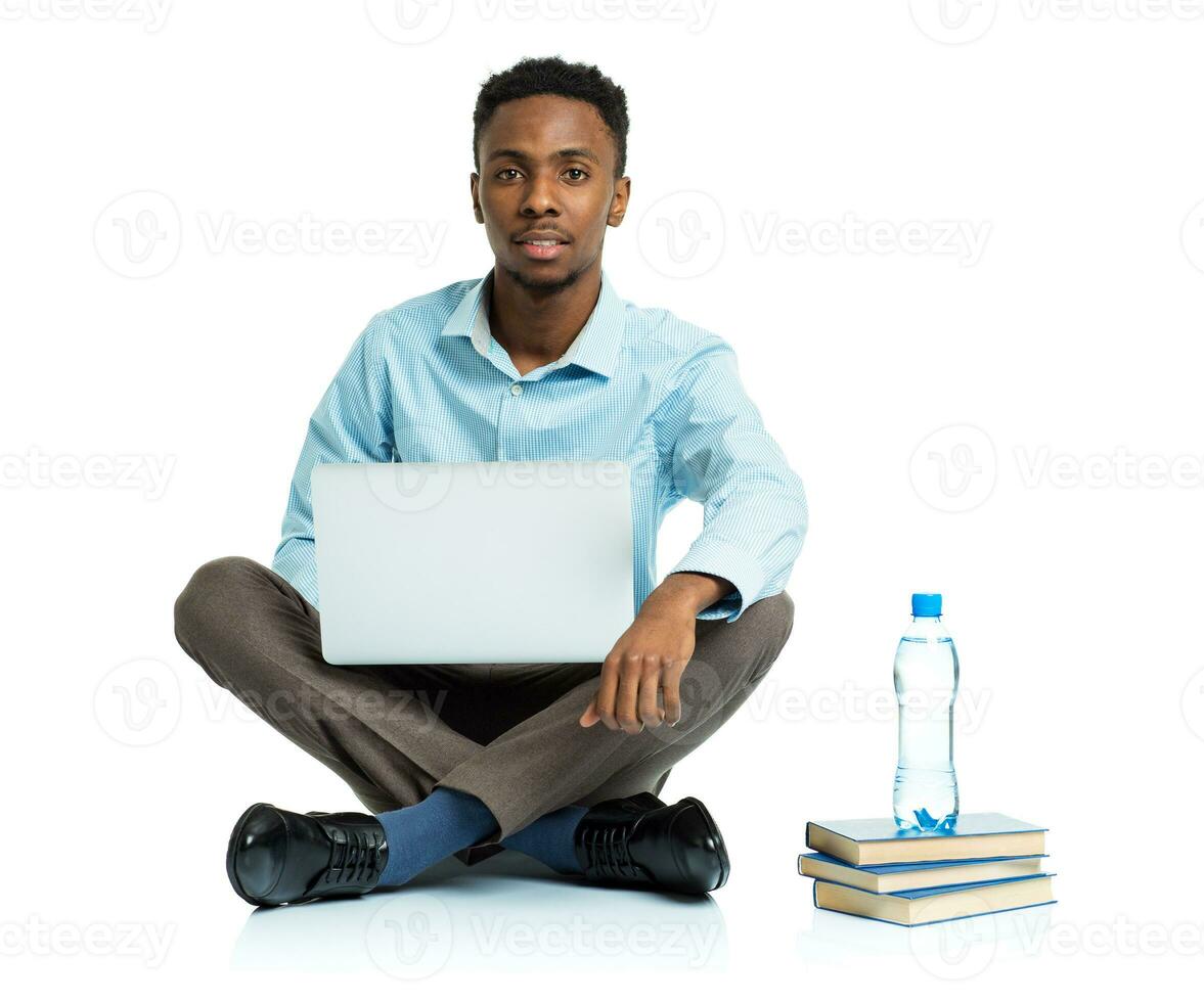 africano americano Faculdade aluna sentado com computador portátil em branco fundo foto