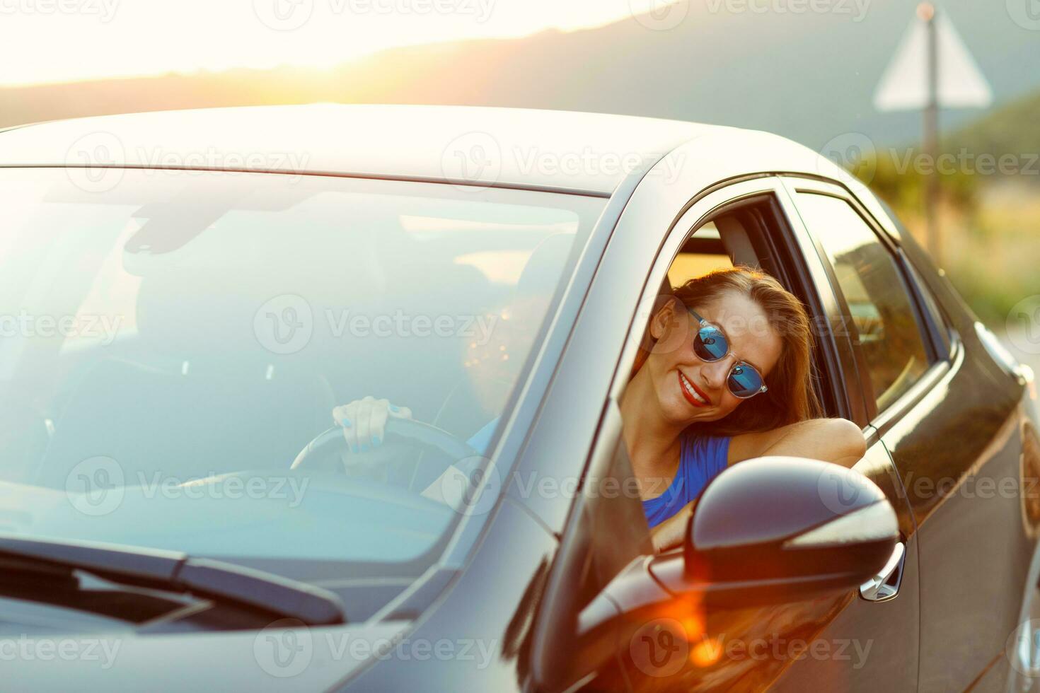 sorridente mulher dirigindo uma carro às pôr do sol foto