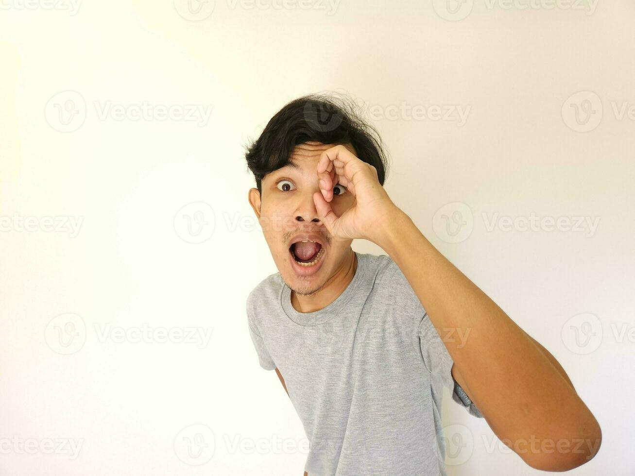 engraçado óbvio espreitar ásia homem dentro cinzento camiseta isolado em branco fundo foto