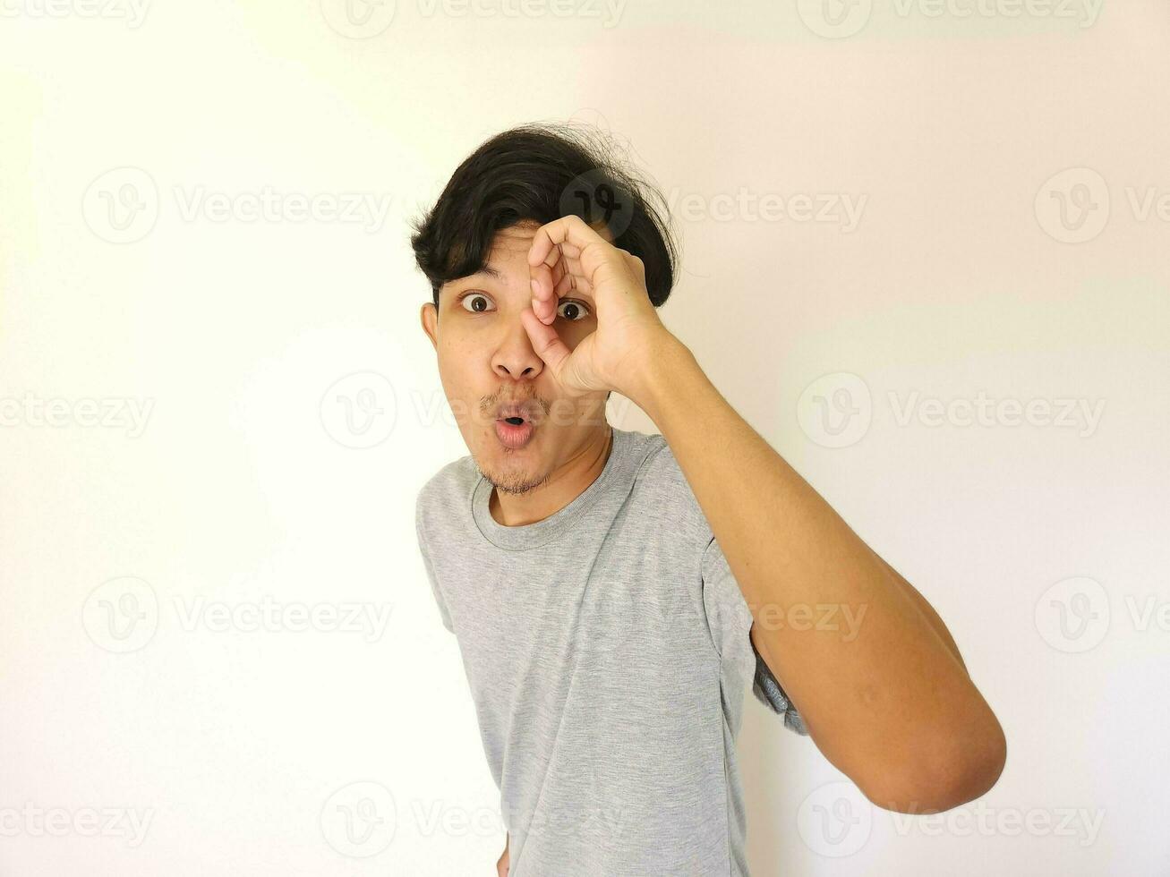 engraçado óbvio espreitar ásia homem dentro cinzento camiseta isolado em branco fundo foto