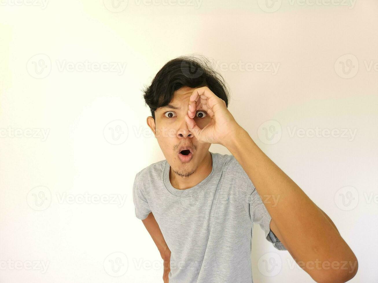 engraçado óbvio espreitar ásia homem dentro cinzento camiseta isolado em branco fundo foto