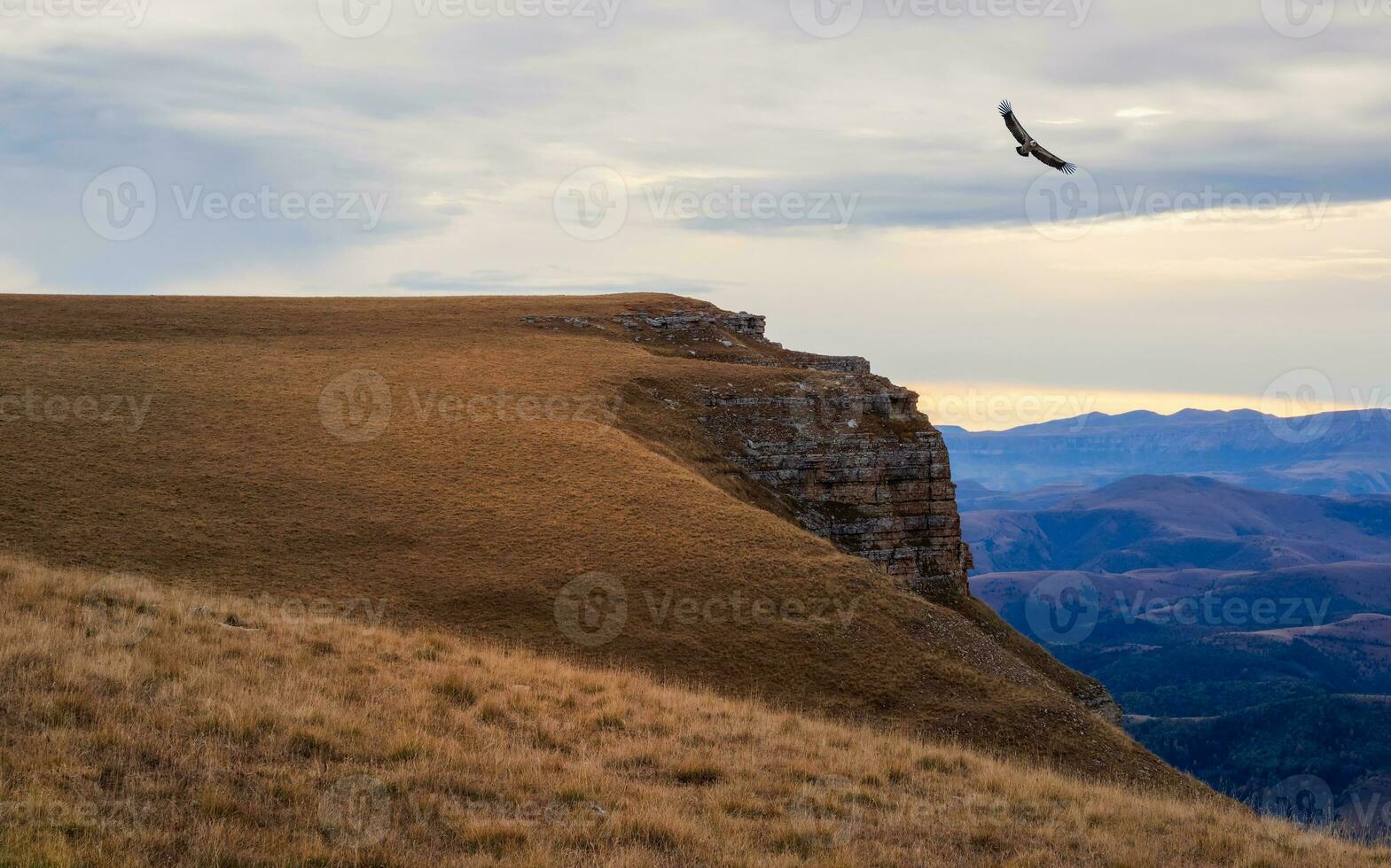 manhã outono panorama com colinas em Alto platô e montanha alcance debaixo dramático nublado céu. a Águia paira sobre a penhasco. vívido cedo manhã outono cores dentro montanhas. foto