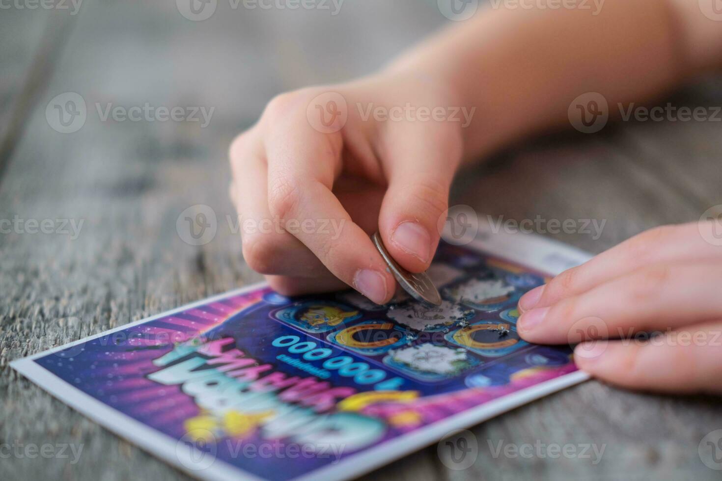 uma criança é mão apaga uma protetora campo dentro uma loteria com uma moeda em uma de madeira fundo. ganho. jogatina, vício. foto