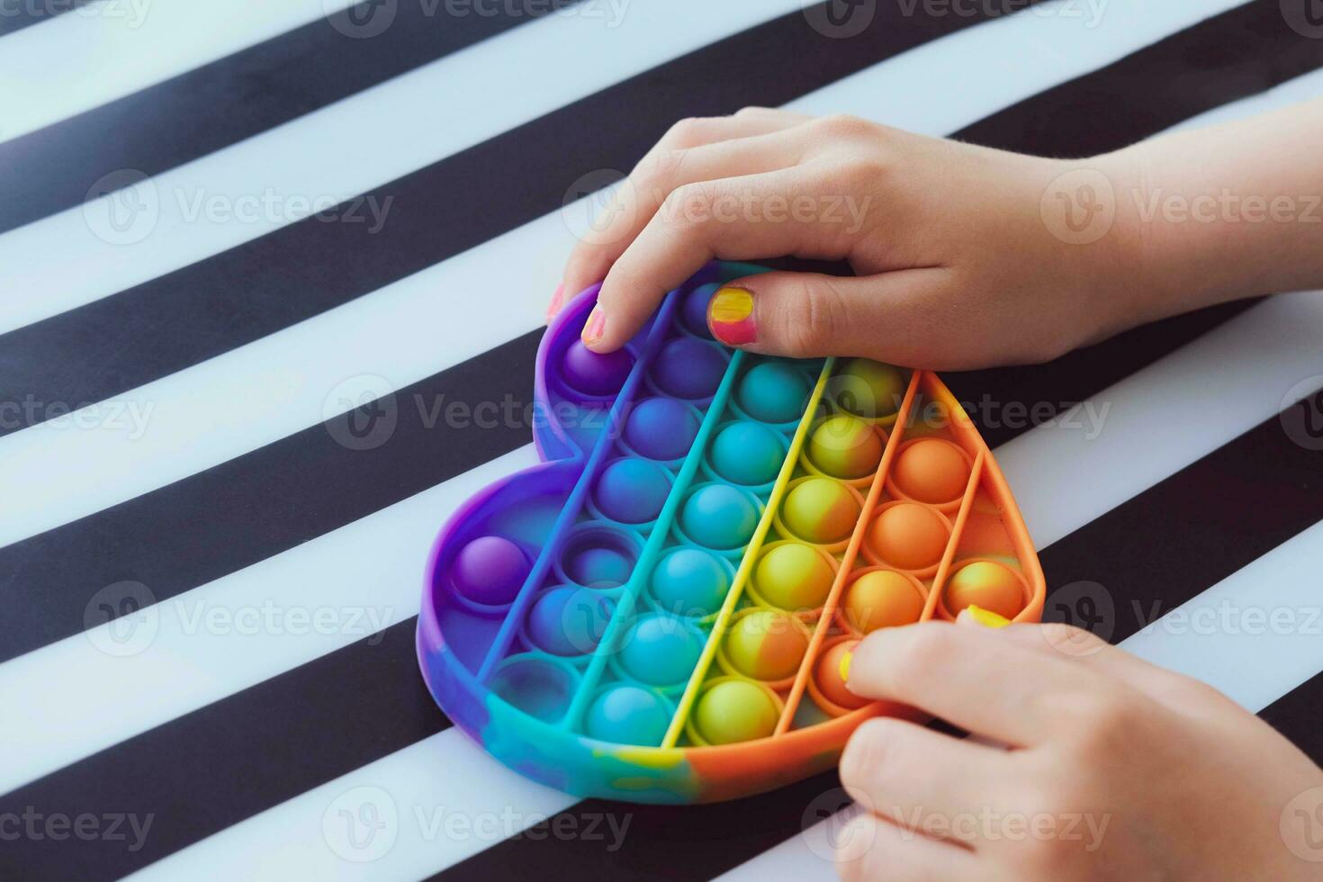 criança jogando com arco Iris pop isto inquietação brinquedo. empurrar bolha inquietação sensorial brinquedo - lavável e reutilizável silício estresse alívio brinquedo. antiestresse brinquedo para criança com especial precisa. foto