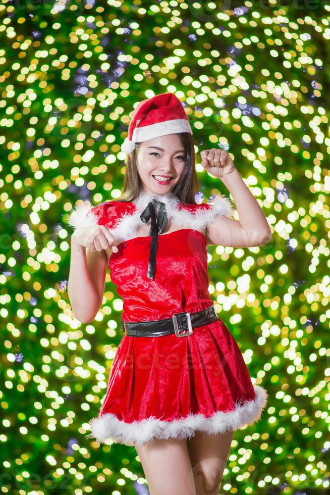 bonita ásia menina dentro santa traje para Natal com noite luz foto