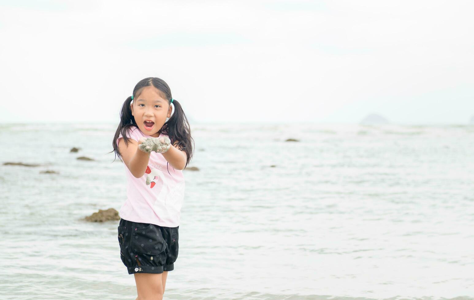 pequeno menina jogar areia em a praia, foto