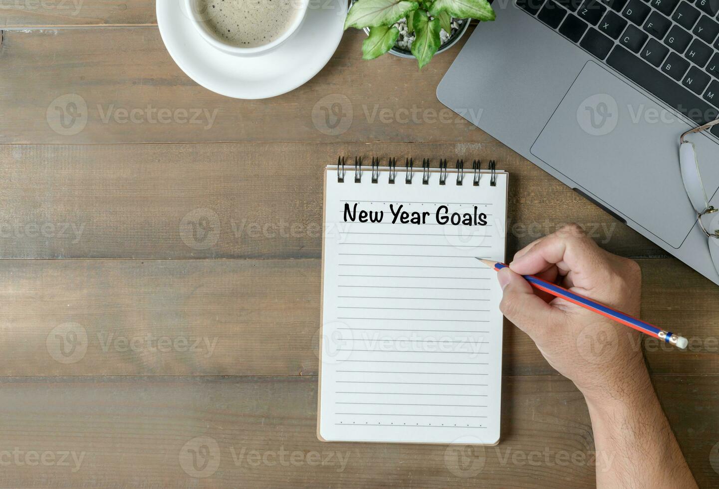 mão homem escrevendo Novo ano metas em Nota papel foto